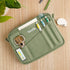 Green Scolla pencil case with stationery items on a wooden surface