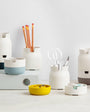 A collection of stackable porcelain-like organizers in various colors, containing pens and other desk items.