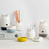 A collection of stackable porcelain-like organizers in various colors, containing pens and other desk items.
