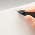 Hand holding a black pen over a white sheet of paper on a gray background