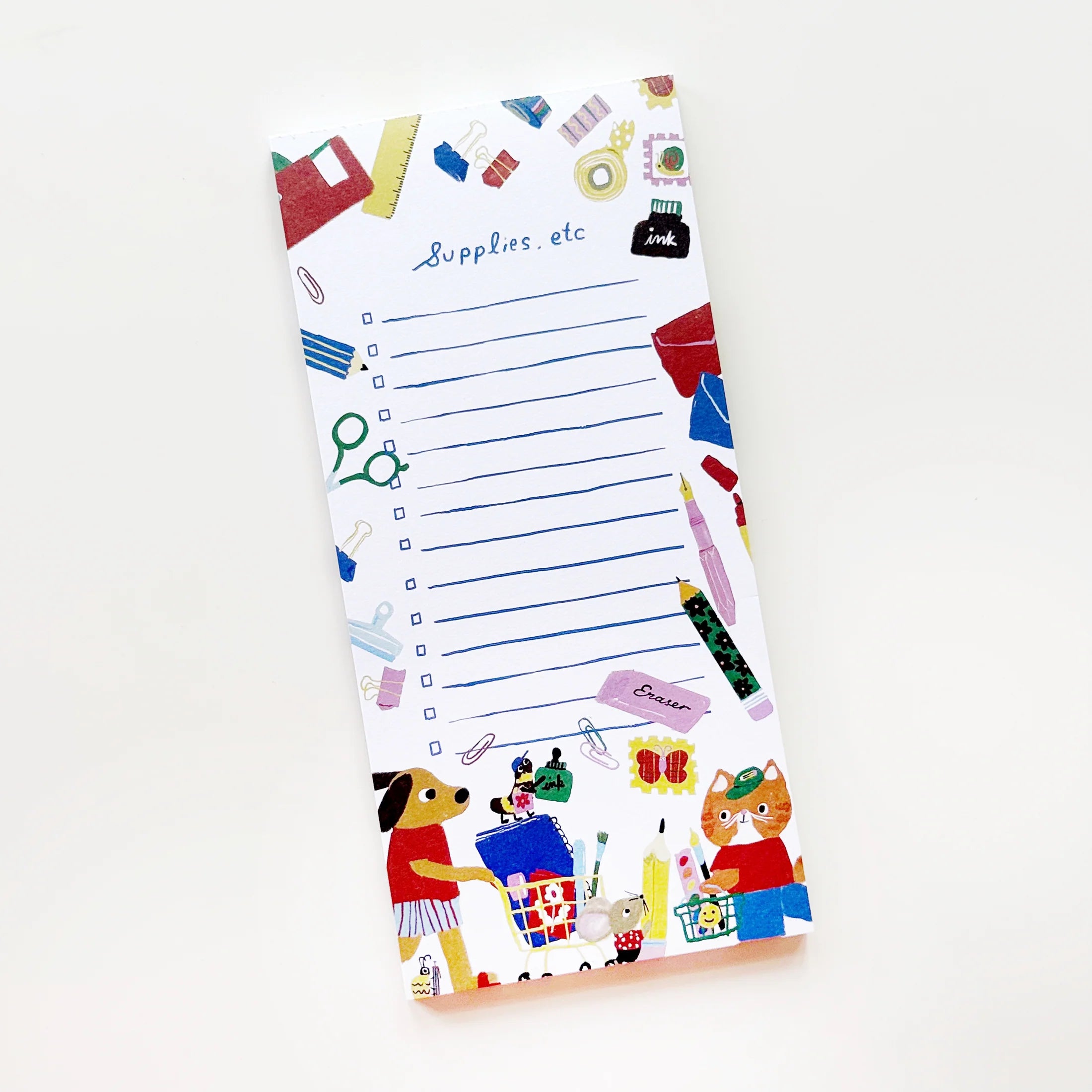 A white notepad with blue lined writing space and colorful doodled stationery icons around the border, photographed on a clean white background.