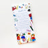 A white notepad with blue lined writing space and colorful doodled stationery icons around the border, photographed on a clean white background.