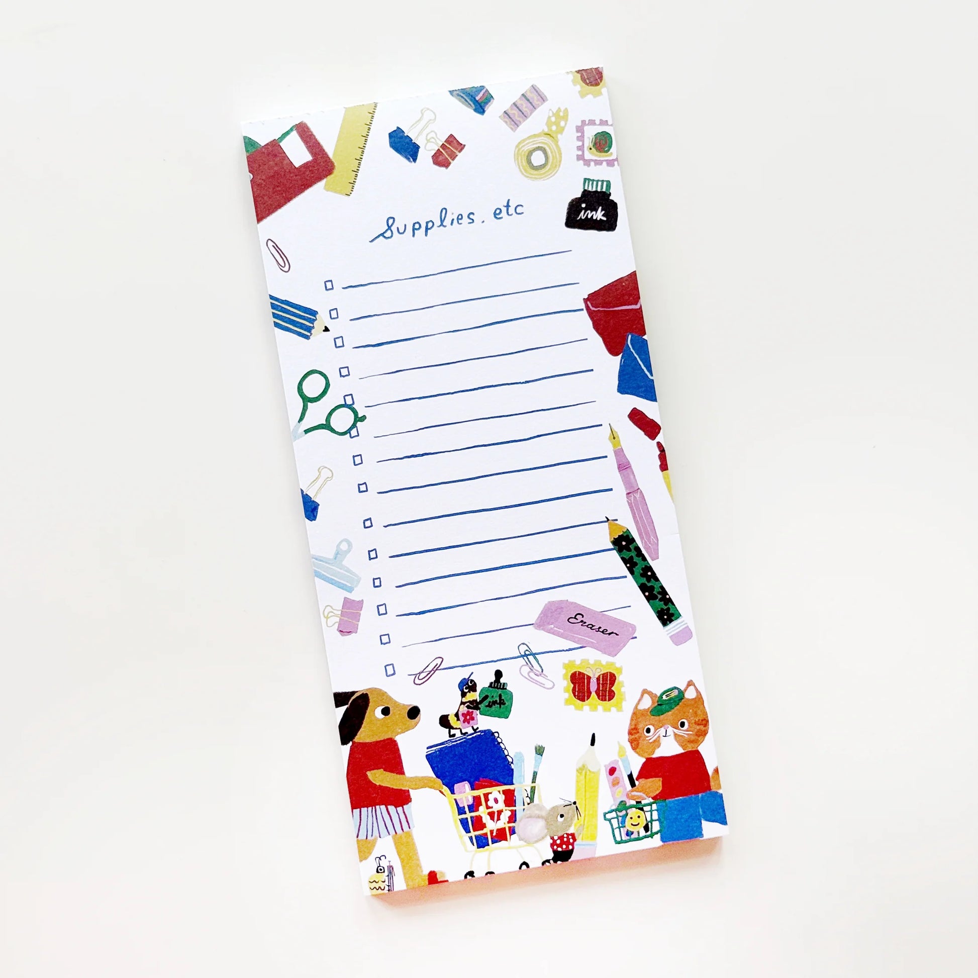 A white notepad with blue lined writing space and colorful doodled stationery icons around the border, photographed on a clean white background.