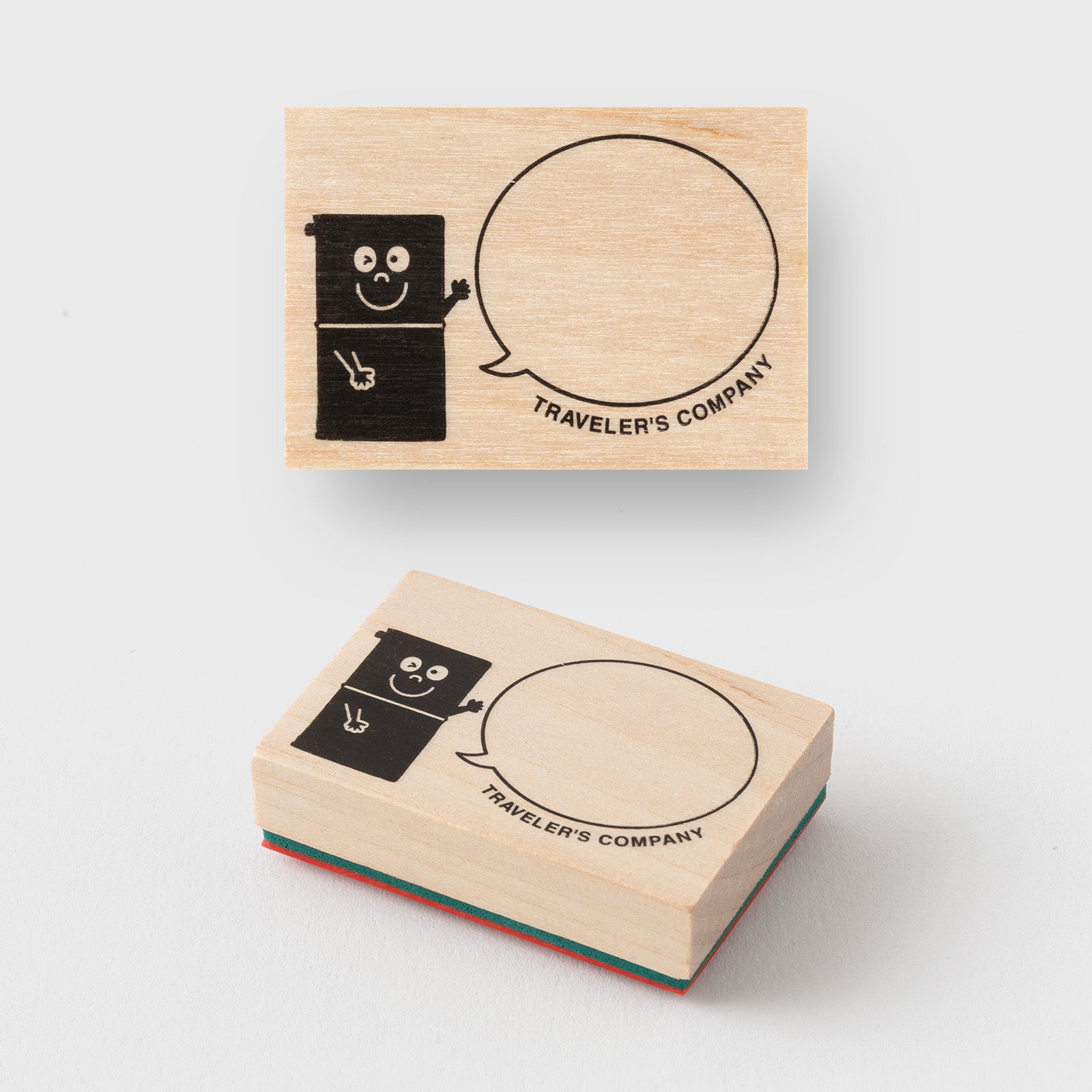 Two wooden stamps with cartoon character and speech bubble design on a white background, branded 'Traveler's Company'.