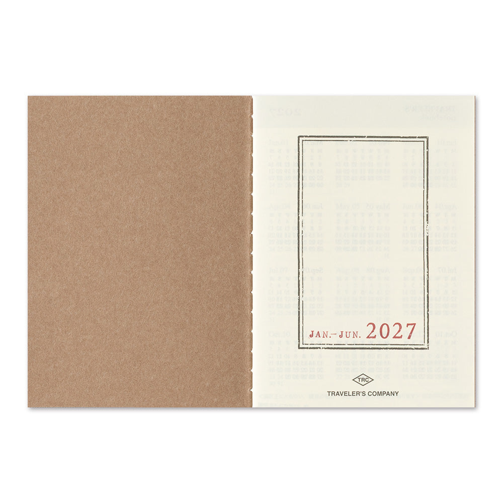 An open kraft paper pocket calendar showing the June 2027 page, with a textured brown cover on the left and an off-white interior page on the right with a red date box and small Traveler's Company logo.