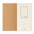 A planner or notebook shown open to a blank page spread, with a large tan kraft-paper left panel and an off-white right panel containing faint calendar grids and the red text '2027' inside a thin rectangular border. Small printed branding at the bottom reads Travelers' Company.
