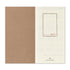 An open planner or notebook showing a kraft brown left page and an off-white right page with faint monthly grids and the red text 'JAN - FEB 2027' plus 'Traveler's Company' at the bottom.