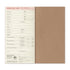 A traveler's departure card notebook shown open, with a tan paper cover and a printed departure card page inside. The card has fields for traveler details and destinations, with the brand name Traveler's Notebook visible at the bottom.