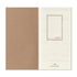 An open planner or calendar showing a kraft brown left page and an off-white right page with faint monthly grids and the red text 'JAN - FEB 2027' inside a thin rectangular border. The brand name 'Traveler's Company' appears at the bottom of the right page.