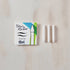 Tom's Studio Ori brush tip packaging with three white candles on a wooden surface