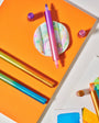 Colorful markers on an orange surface with a white background
