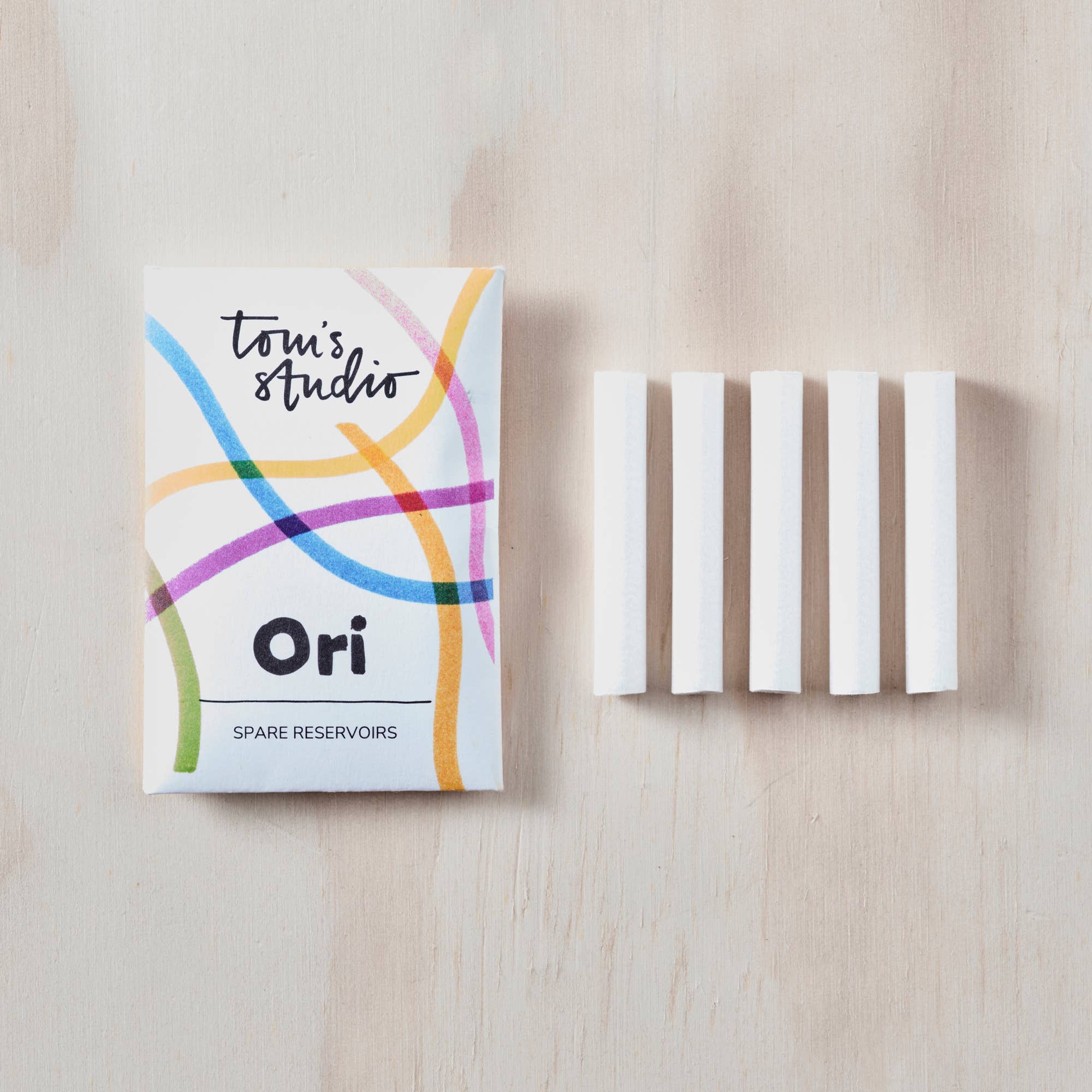 Toni's Studio Ori spare reservoirs packaging with white strips on a light wooden surface