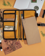 Organized stationery items including a notebook, pen, and paper clips on an orange background.