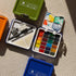 Watercolor paint sets in various colors on a textured surface