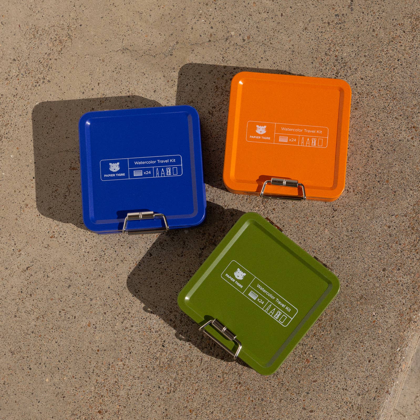 Three portable trash bins in blue, orange, and green on a concrete surface.