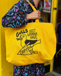 Person holding a yellow tote bag with a graphic design and text.