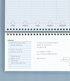 An open spiral-bound planner or notebook with Korean text, lined pages, weekly section headers, a checklist on the left page, and handwritten notes on the right, photographed against a light blue-gray background.