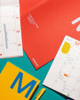 Colorful planner books with a pen on a teal background
