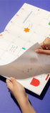 Person holding a planner with colorful stickers on a blue background