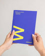 Person holding a blue planner with a yellow 'M' on a white background